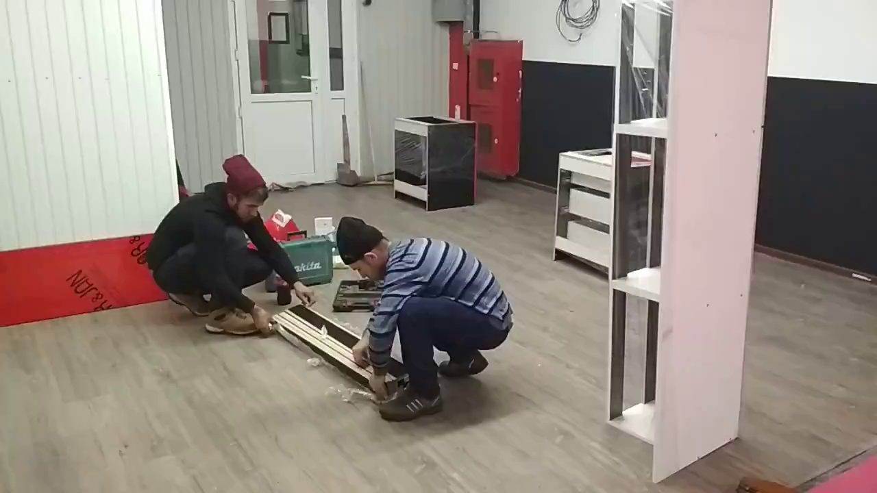Сборка длинной чёрной детали на полу зала