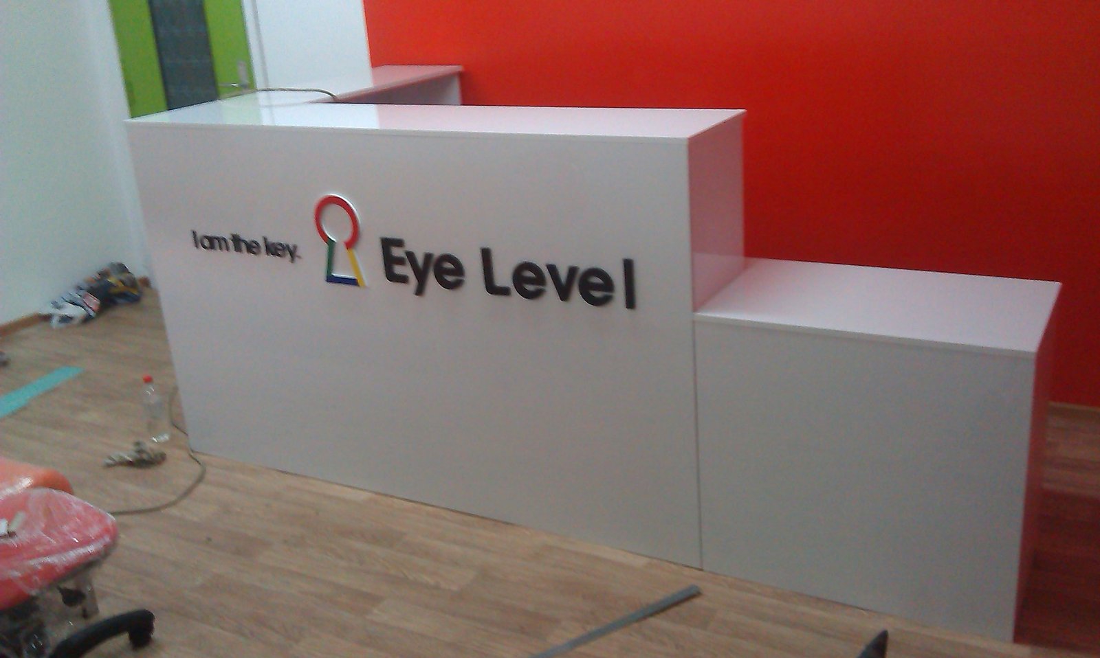 Ресепшен Eye Level: белая стойка с логотипом на красной стене