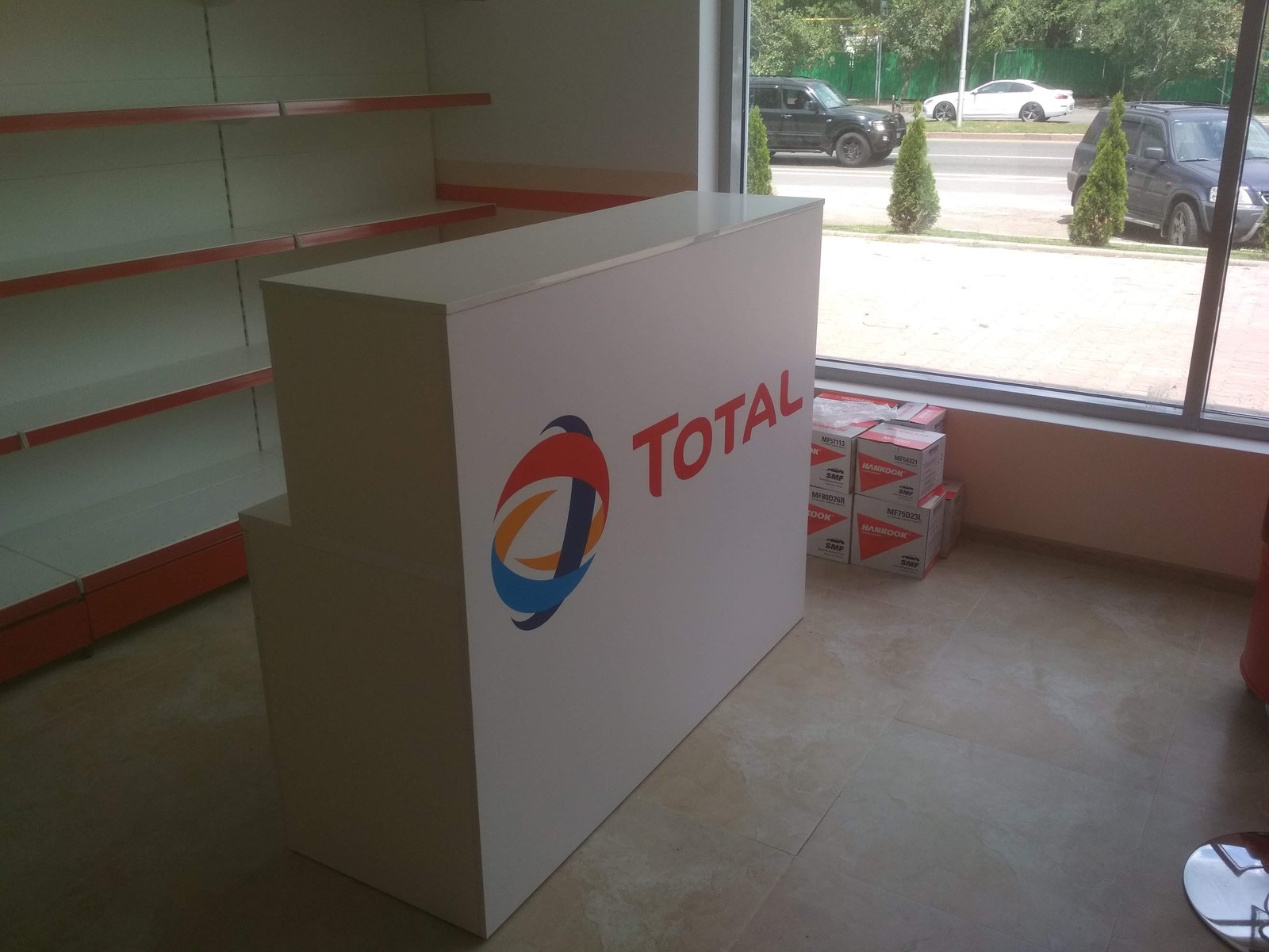 Белая стойка с логотипом TOTAL у окна