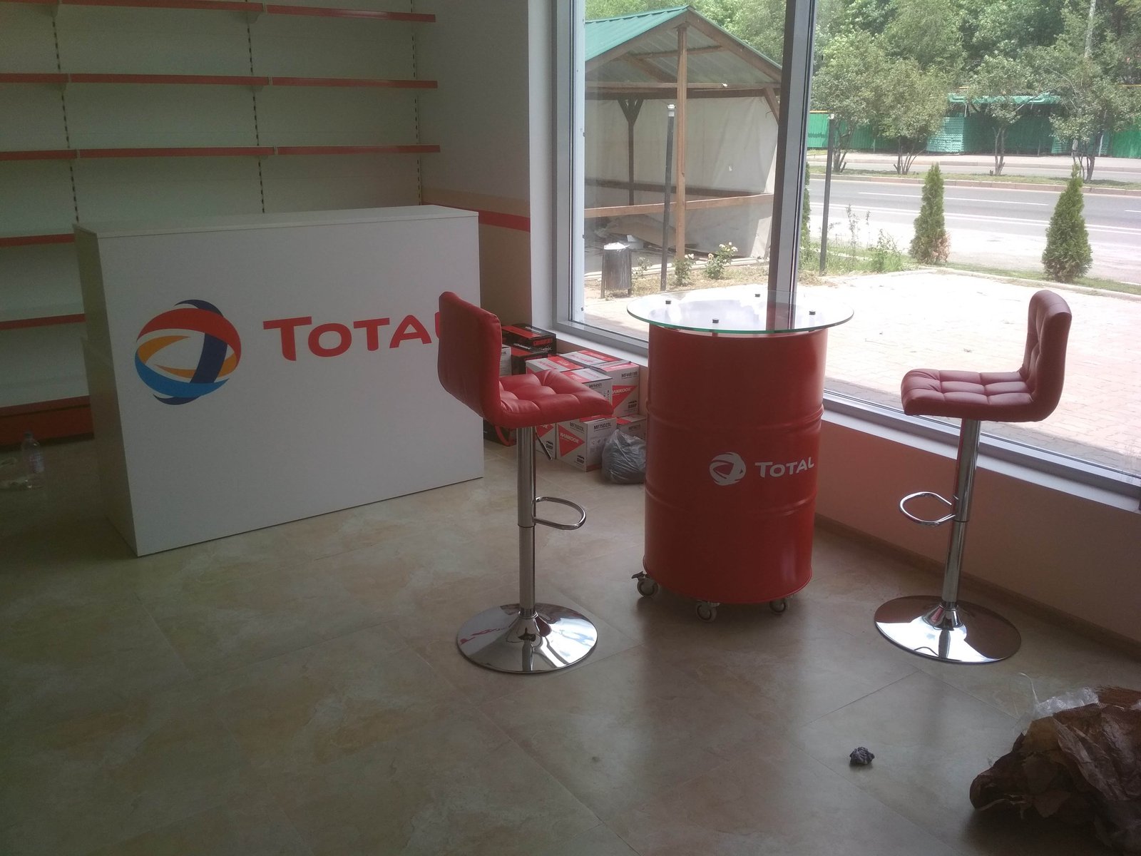 Стойка с логотипом TOTAL и столы из бочек со стульями