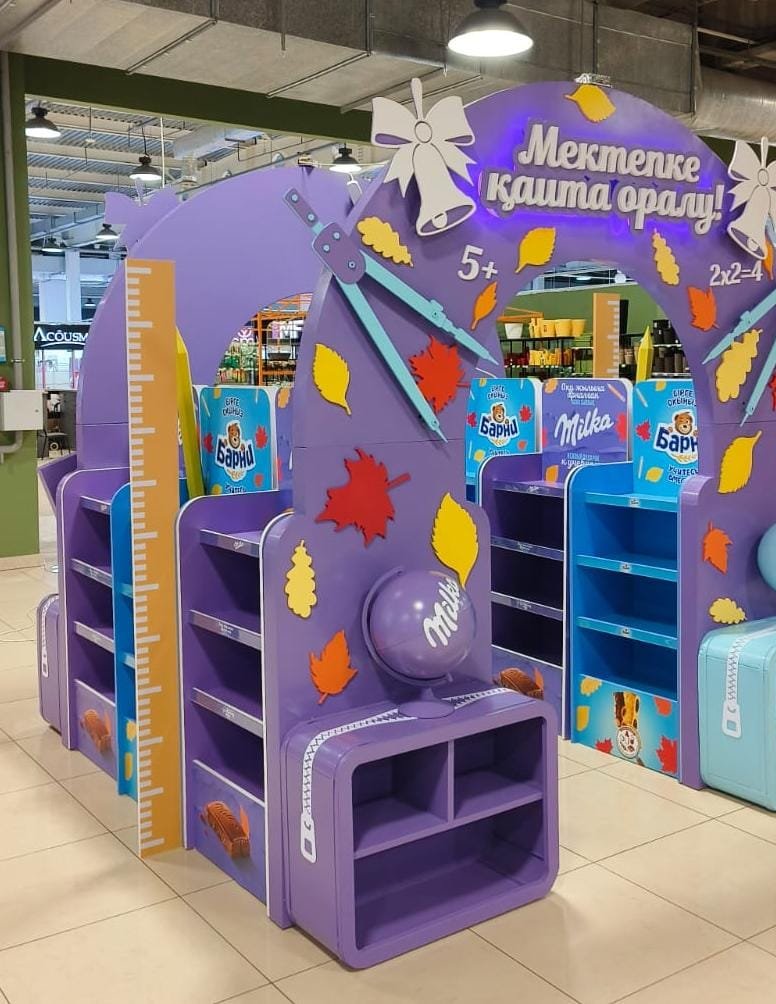 Фасад зоны на казахском языке: арка с вывеской, стеллажи и глобус